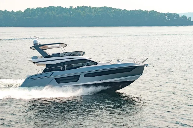Slide: The Image of 2023 Azimut Fly 53 yacht cruising on a serene lake with lush green shoreline. - 20
