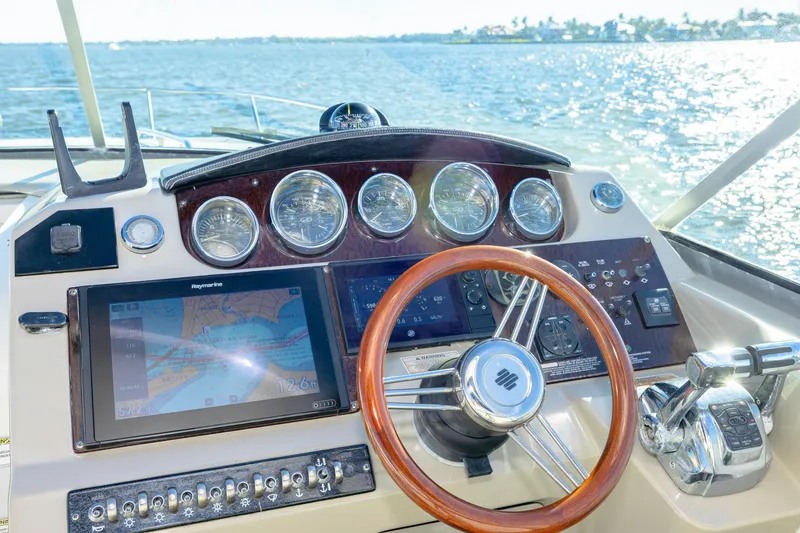 Slide: The Image of Cockpit of 2013 Sea Ray 370 Venture with navigation screens and wooden steering wheel. - 12