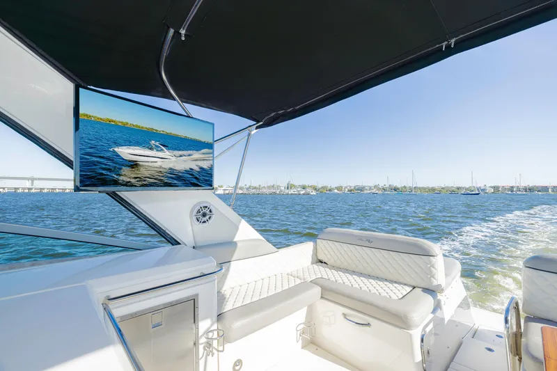 Slide: The Image of 2013 Sea Ray 370 Venture boat interior with TV, luxurious seating, and ocean view. - 16