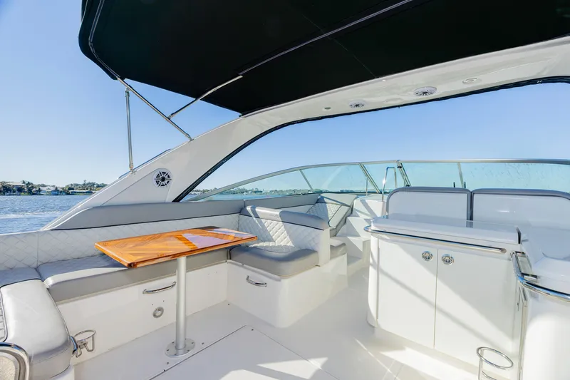 Slide: The Image of 2013 Sea Ray 370 Venture boat interior with seating and table, under a canopy. - 19