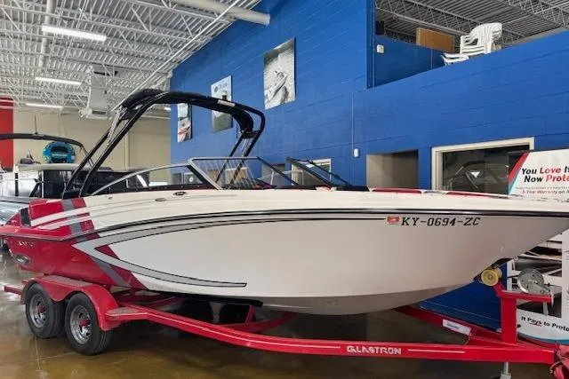 The Image of 2014 Glastron GTS 225 boat on red trailer in showroom. - 0