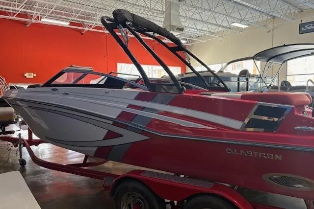 Slide: The Image of 2014 Glastron GTS 225 boat in showroom, red and white design, on trailer. - 1