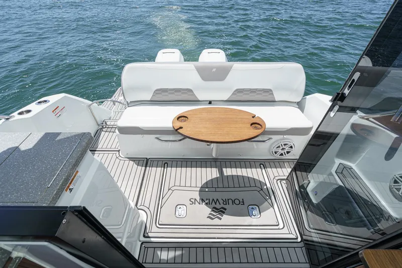Slide: The Image of 2020 Four Winns Vista 355 Coupe OB boat interior with seating and table on water. - 20