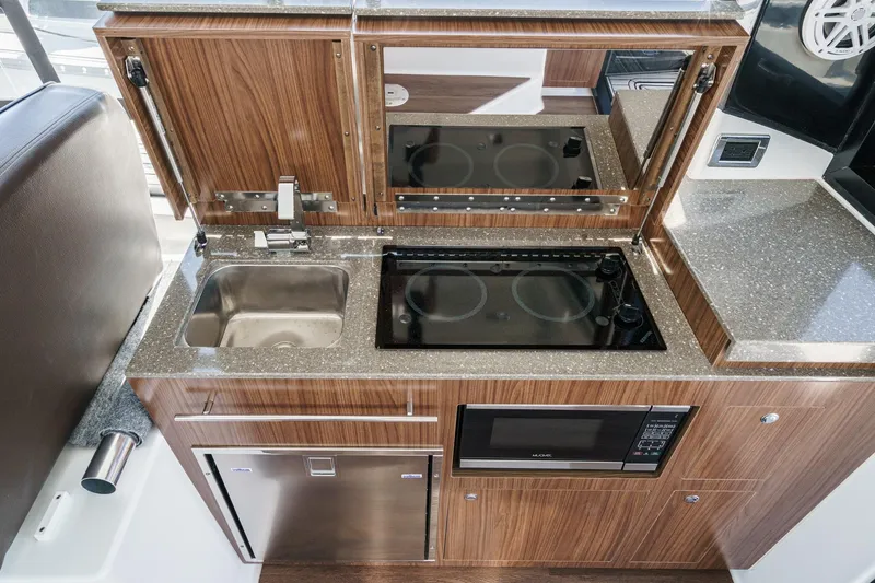 Slide: The Image of Modern kitchen area in 2020 Four Winns Vista 355 Coupe OB yacht, featuring sink, stove, and microwave. - 29