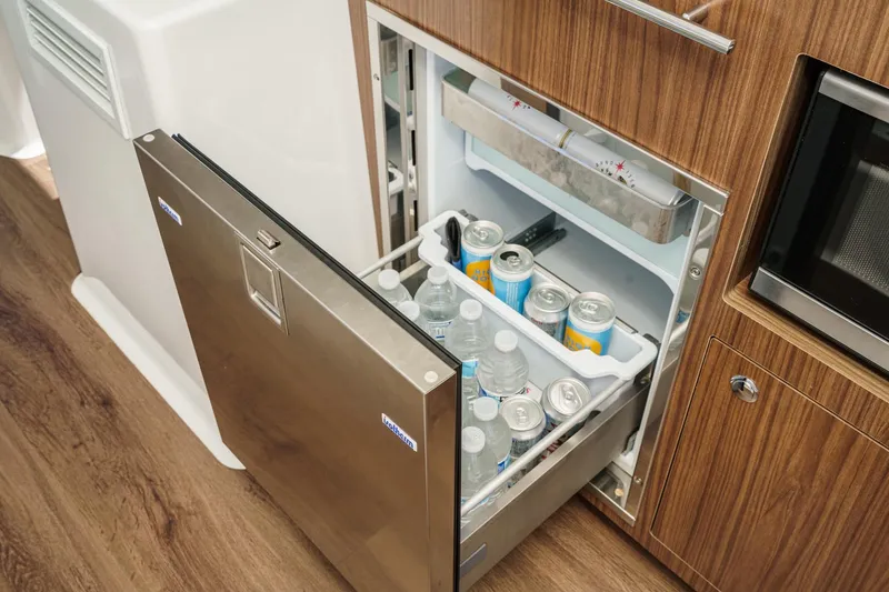 Slide: The Image of Mini fridge stocked with drinks in 2020 Four Winns Vista 355 Coupe OB boat interior. - 31