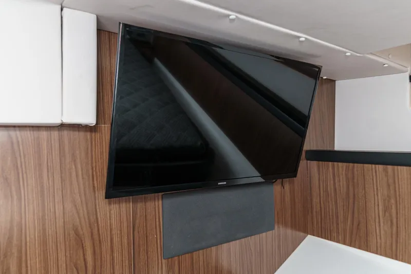 Slide: The Image of Wall-mounted TV in 2020 Four Winns Vista 355 Coupe OB interior, featuring wood paneling. - 53