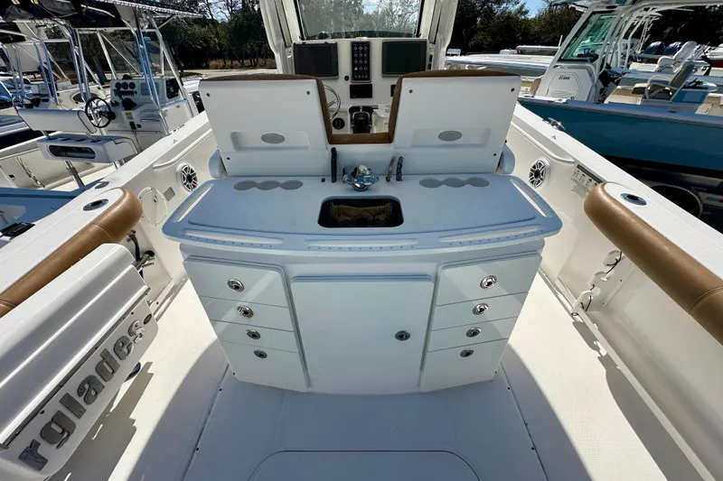 Slide: The Image of 2013 Everglades 325 Center Console boat with dual outboard engines, parked on gravel. - 2