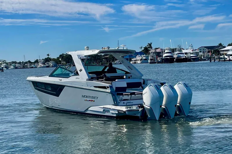 Slide: The Image of 2022 Monterey 385SS Super Sport boat cruising in a marina under a clear blue sky. - 1