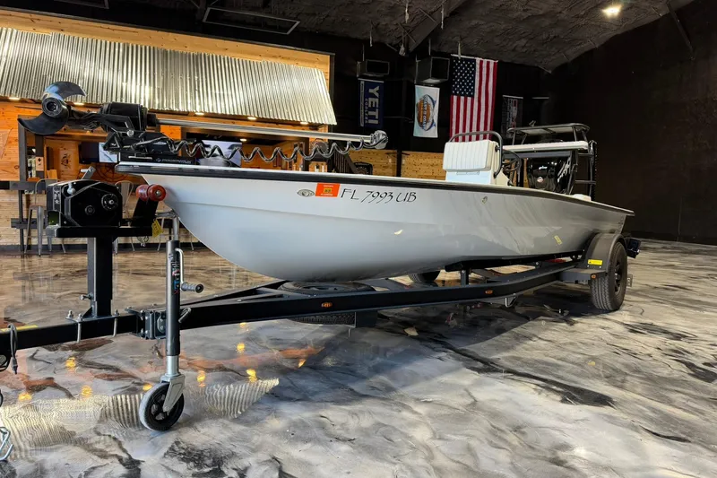 Slide: The Image of 2026 Hell's Bay Marquesa boat on trailer in a showroom with American flag. - 3
