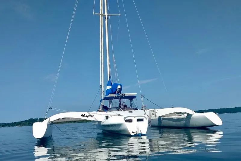 The Image of Sleek 2012 Kurt Hughes 40 trimaran sailboat on calm water under clear blue sky. - 0