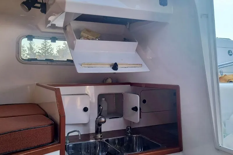 Slide: The Image of Interior of a 2012 Hughes 40 boat, featuring a compact kitchen with sink and storage. - 19