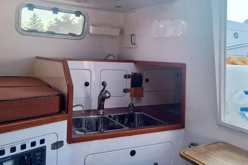 Slide: The Image of Compact kitchen area in a 2012 Hughes 40 boat, featuring a sink and storage cabinets. - 20