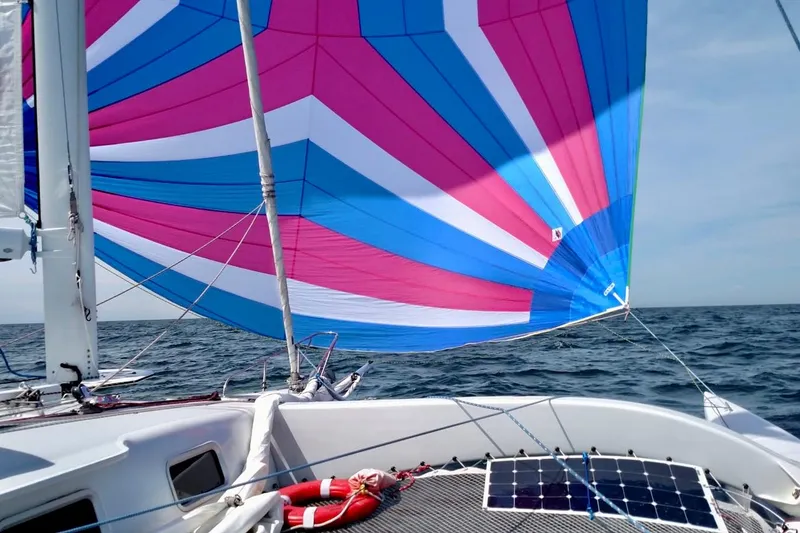Slide: The Image of Sailboat with colorful spinnaker sail on open sea, featuring solar panels on deck. - 6