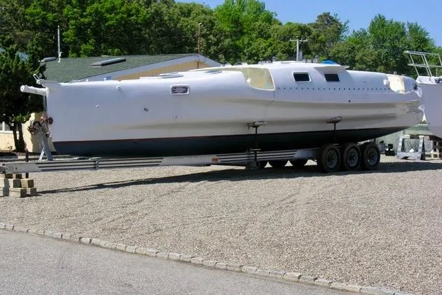 Slide: The Image of Hughes 40 sailboat on trailer, 2012 model, parked on gravel lot with trees in background. - 7