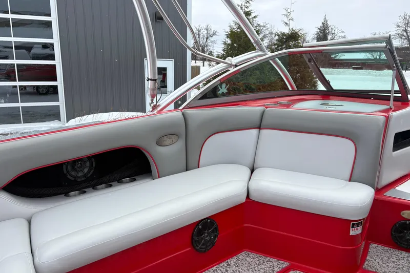 Slide: The Image of 2006 Centurion Enzo SV230 boat interior with red and gray seating, speaker, and cup holders. - 9