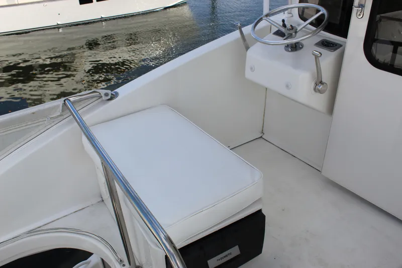 Slide: The Image of 2003 Ocean Yachts 65 Odyssey helm with white seating and steering wheel. - 57
