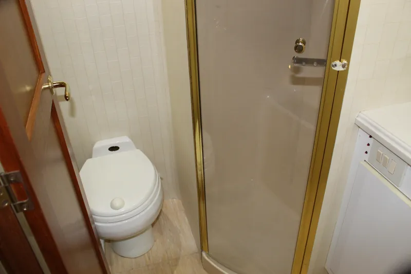 Slide: The Image of Bathroom in 2003 Ocean Yachts 65 Odyssey, featuring toilet and shower with gold trim. - 66