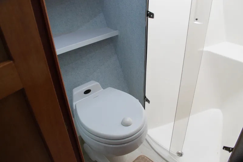 Slide: The Image of Bathroom interior of 2003 Ocean Yachts 65 Odyssey, featuring a compact toilet and shower. - 87