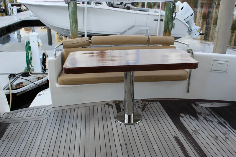 Slide: The Image of 2003 Ocean Yachts 65 Odyssey yacht deck with wooden table and cushioned seating. - 95