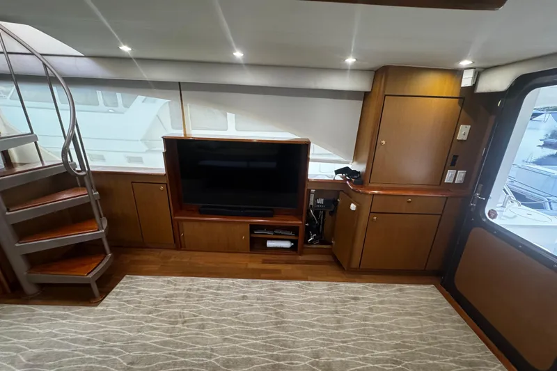Slide: The Image of Luxurious interior of 2003 Ocean Yachts 65 Odyssey with TV, cabinets, and spiral staircase. - 25