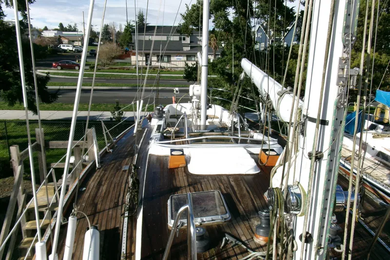 Slide: The Image of 1980 Ketch 51 sailboat deck with rigging and wooden finish, docked near residential area. - 12