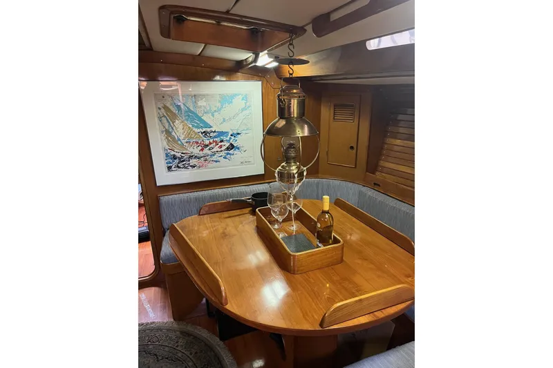 Slide: The Image of Cozy 1980 SKYE 51 yacht interior with wooden dining table, nautical decor, and hanging lantern. - 3