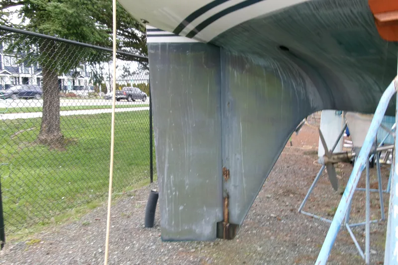 Slide: The Image of 1980 Ketch 51 sailboat hull and rudder on dry dock, near a fence. - 8