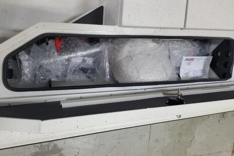 Slide: The Image of 2024 Ranger RB210 storage compartment with bubble-wrapped items and documents. - 7