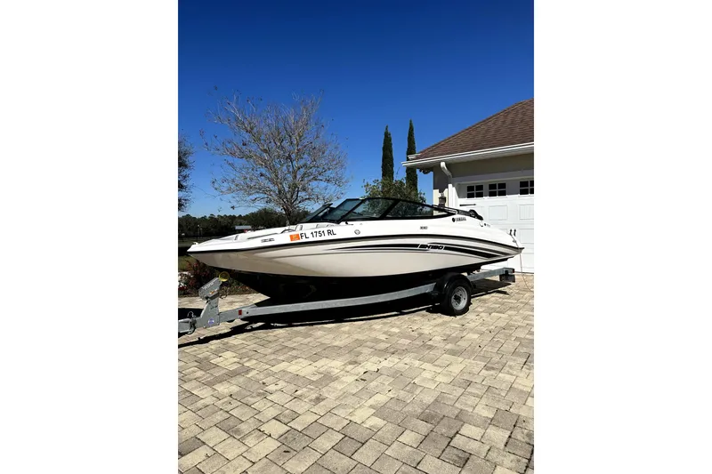 The Image of 2017 Yamaha Boats SX190 on trailer, parked on a paved driveway under clear blue sky. - 0