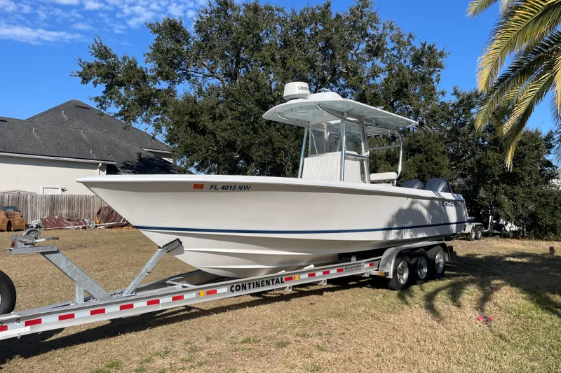 The Image of 2008 Contender 27 Tournament boat on trailer, parked on grass with trees and house in background. - 1