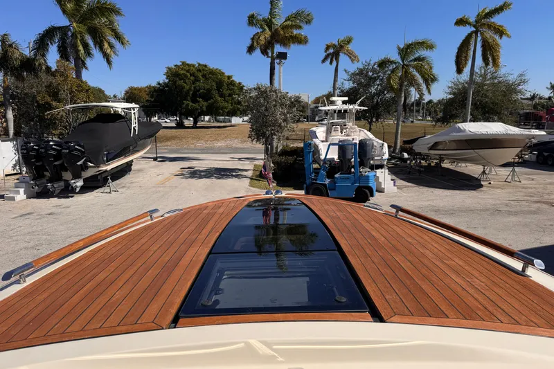 Slide: The Image of 2019 Chris-Craft Corsair 30 boat with wooden deck, parked near palm trees. - 16