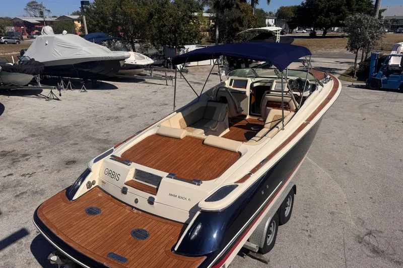 Slide: The Image of 2019 Chris-Craft Corsair 30 boat with wooden deck and canopy, parked on a trailer. - 2