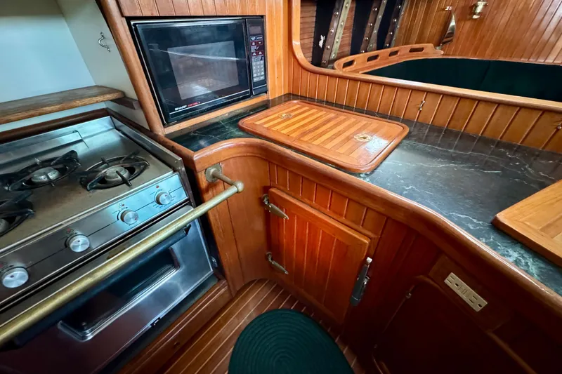 Slide: The Image of Galley kitchen in 1988 Hans Christian Christina yacht with stove, microwave, and wooden cabinetry. - 11