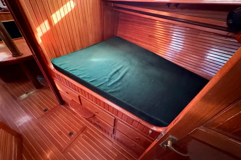 Slide: The Image of 1988 Hans Christian Christina cabin interior with wooden paneling and green cushioned berth. - 19