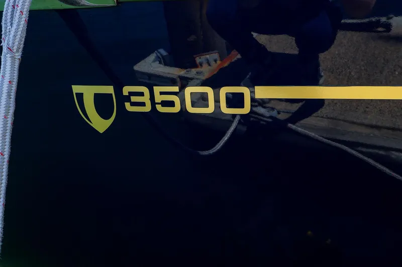 Slide: The Image of Tartan 3500 sailboat logo on dark hull, featuring yellow text and emblem. - 20