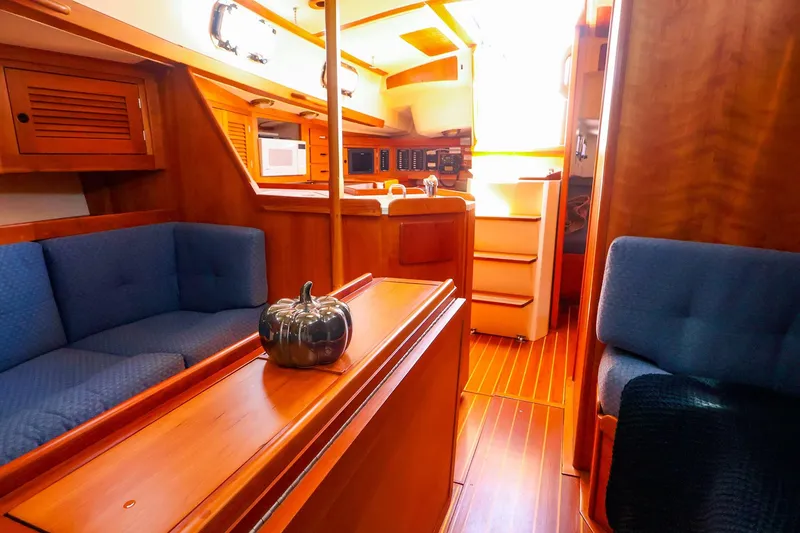 Slide: The Image of Interior of a 1999 Tartan 3500 sailboat with wooden finishes and blue seating. - 26