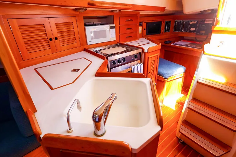 Slide: The Image of Interior of a 1999 Tartan 3500 yacht featuring a compact kitchen with wooden cabinetry. - 33
