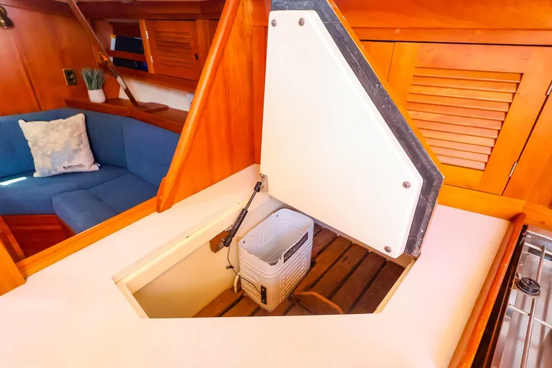 Slide: The Image of Interior of 1999 Tartan 3500 sailboat with open storage compartment and blue seating area. - 35