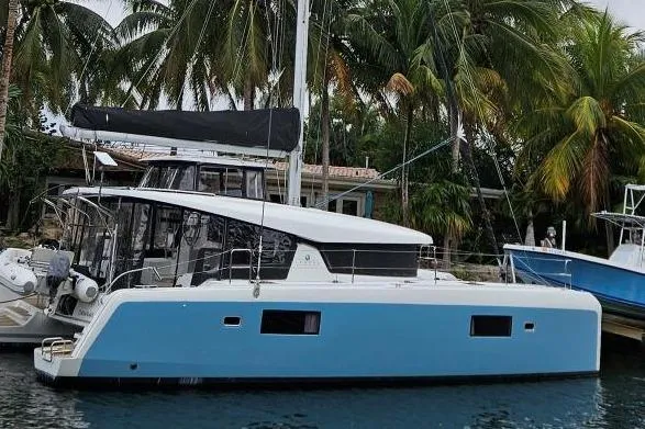 The Image of 2017 Lagoon 42 catamaran docked near palm trees under cloudy sky. - 0