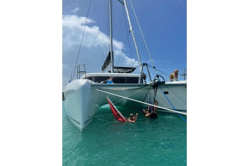 Slide: The Image of 2017 Lagoon 42 catamaran with people relaxing in hammocks and a dog on deck. - 3