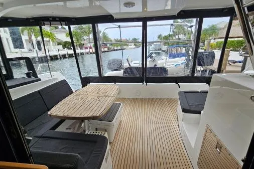 Slide: The Image of 2017 Lagoon 42 catamaran interior with wooden flooring and seating, docked by a canal. - 48