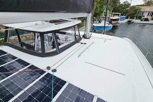 Slide: The Image of 2017 Lagoon 42 catamaran with solar panels docked by the water. - 57
