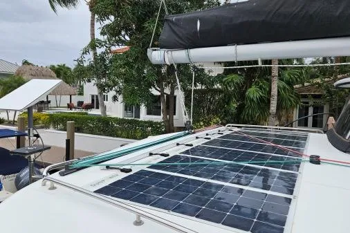 Slide: The Image of 2017 Lagoon 42 catamaran with solar panels on deck, docked near tropical foliage. - 58