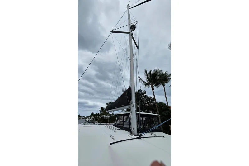 Slide: The Image of 2017 Lagoon 42 catamaran with mast and sails, set against a cloudy sky and palm trees. - 66