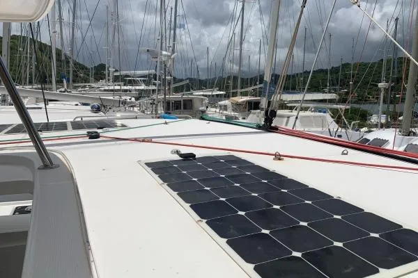 Slide: The Image of 2017 Lagoon 42 catamaran with solar panels docked at a marina under cloudy skies. - 72