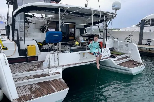 Slide: The Image of Child sitting on 2017 Lagoon 42 catamaran, docked at marina, with nautical equipment visible. - 73