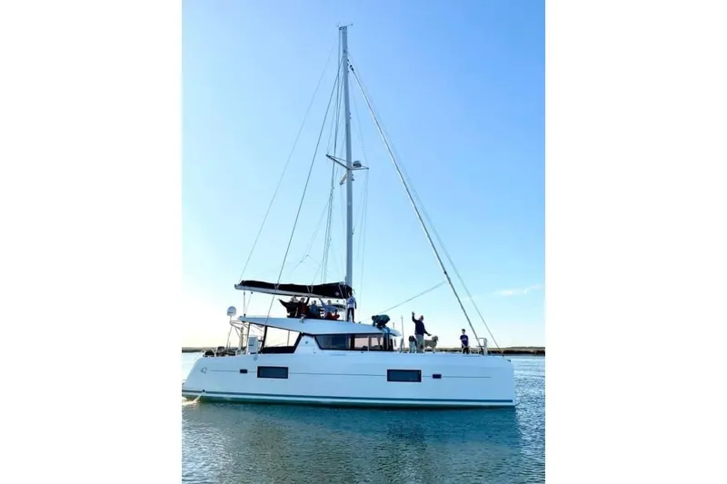 Slide: The Image of 2017 Lagoon 42 yacht with Zodiac tender docked near waterfront homes. - 83