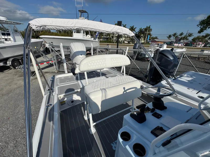 Slide: The Image of 2024 Contender 26 Bay boat with white seating and console, displayed outdoors under a clear sky. - 18