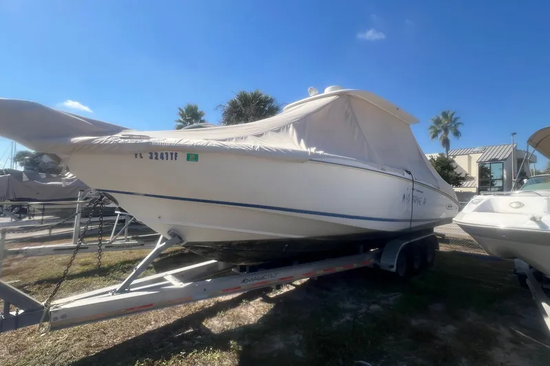 The Image of 2005 Boston Whaler 320 Outrage boat on trailer, covered, with clear blue sky background. - 0