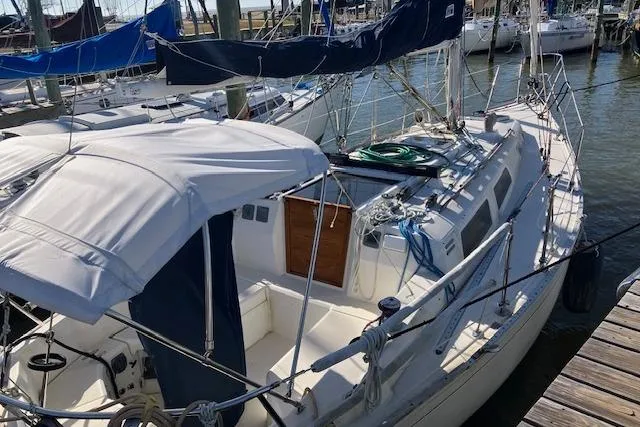 Slide: The Image of 1989 Sabre 30 sailboat docked at marina, featuring white canopy and blue accents. - 2